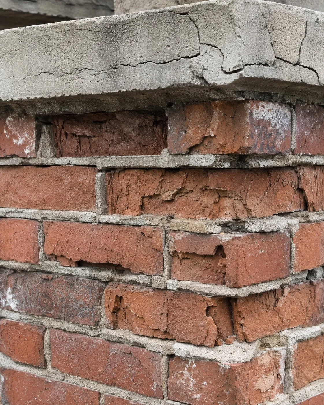 Close view of spalled brick and open mortar joints on a chimney