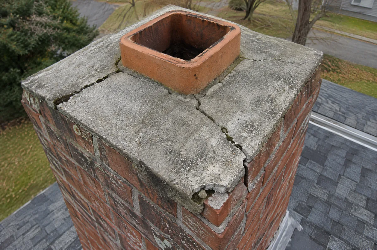 Cracked concrete chimney crown around a clay flue tile